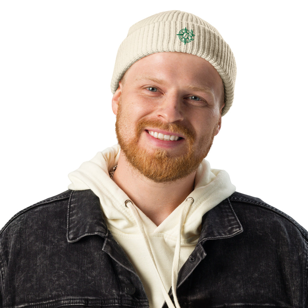 Man wearing a beige beanie with '54 North' logo and a denim jacket on a white background