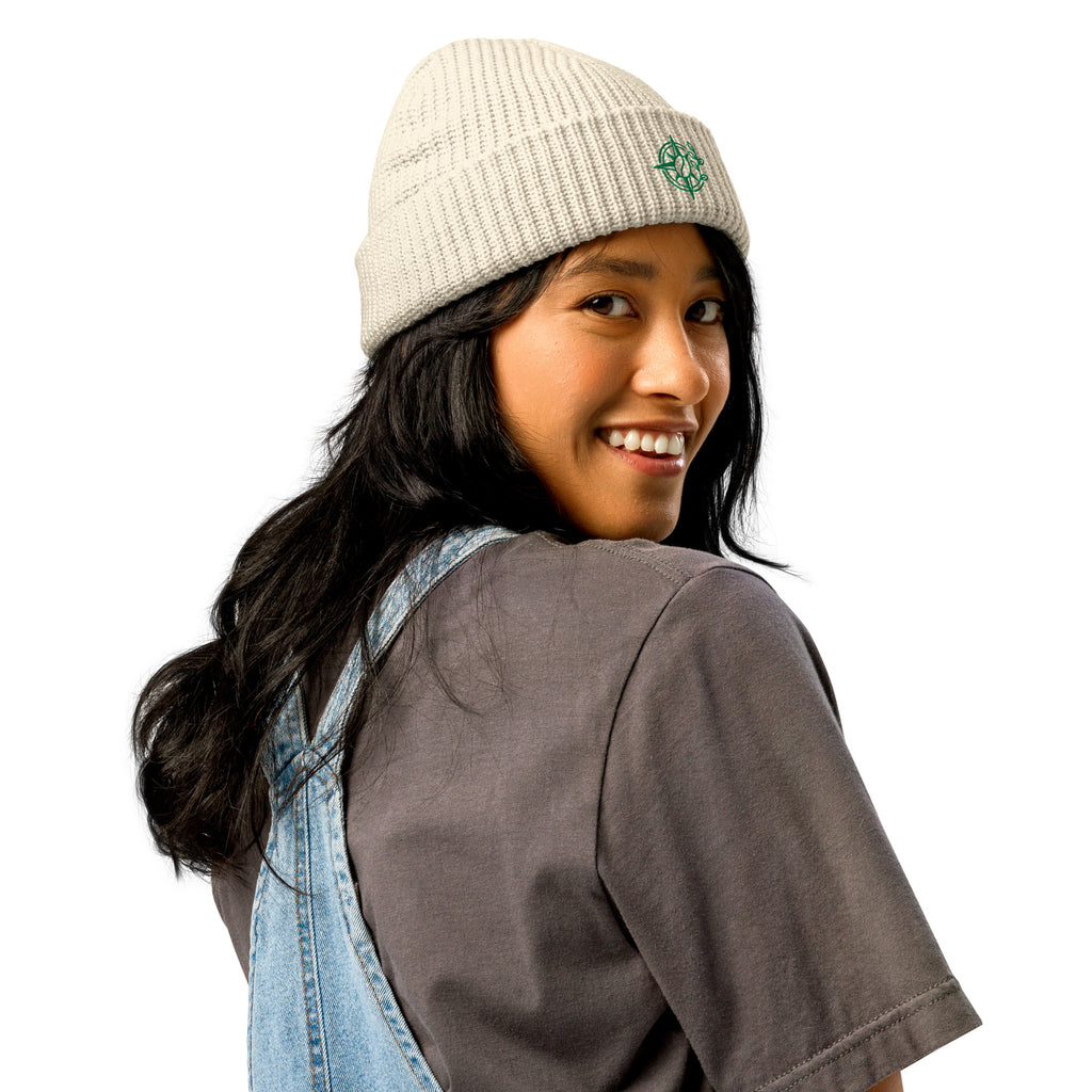Person wearing a beige knit beanie and denim overalls on a white background