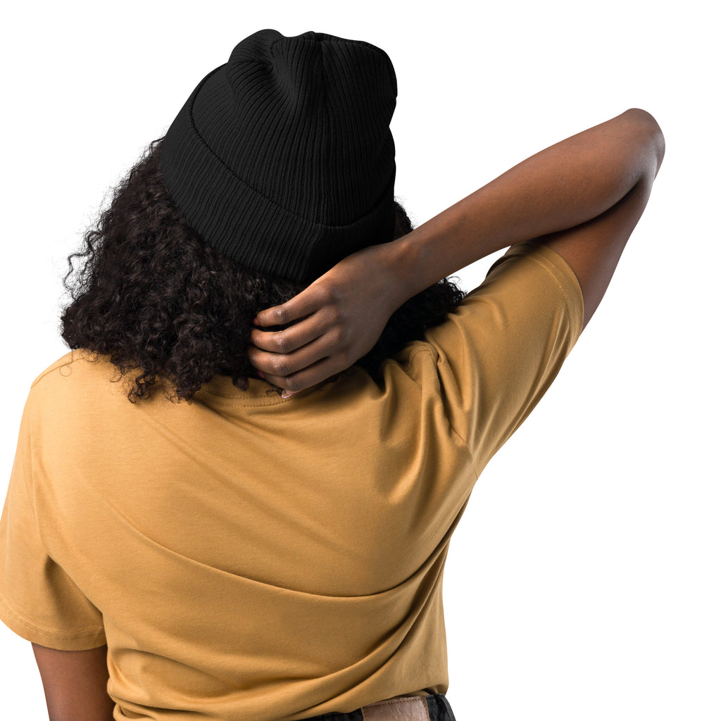 Person wearing a black beanie and mustard yellow shirt on a white background