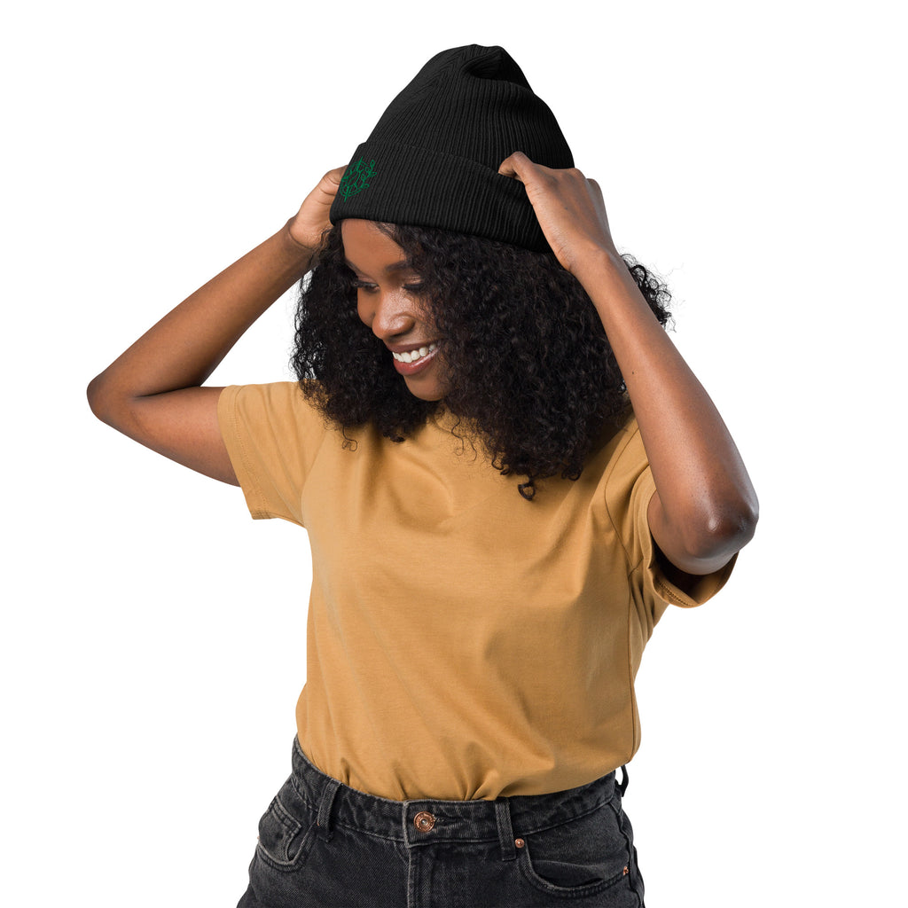 Woman wearing a black beanie and mustard yellow shirt on a white background