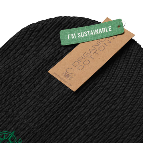 Close-up of a black ribbed knit beanie with a green 'I'M SUSTAINABLE' hangtag and a brown paper tag reading 'ORGANIC COTTONS' on a white background.